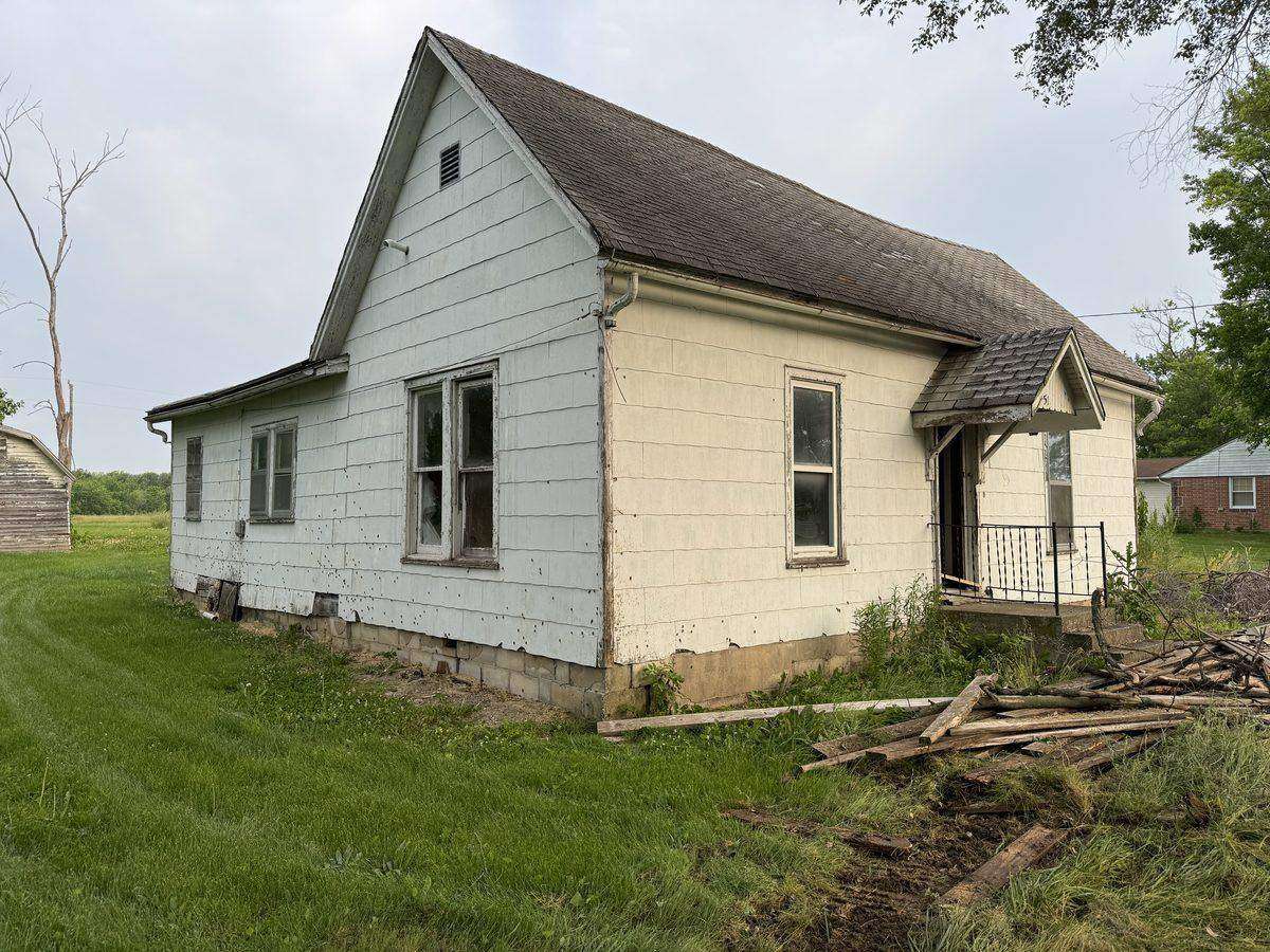 Older house with cement-board siding staged for an Atlas teardown in Mid-Missouri, the kind of pre-1980 structure that gets an asbestos inspection before demolition in Missouri