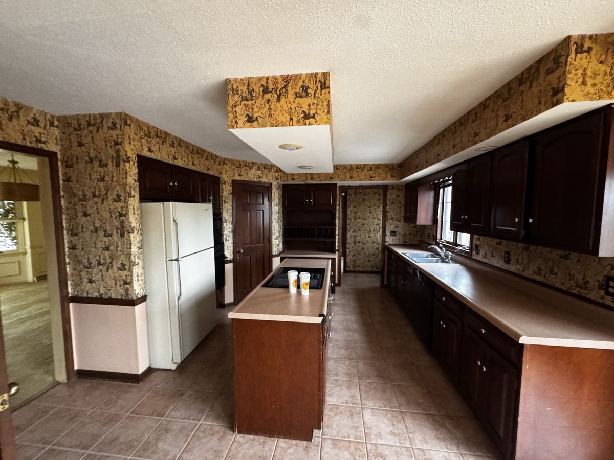 Kitchen of an older house near Columbia, MO ahead of demolition, with the original flooring and wallboard an asbestos inspector samples before the teardown