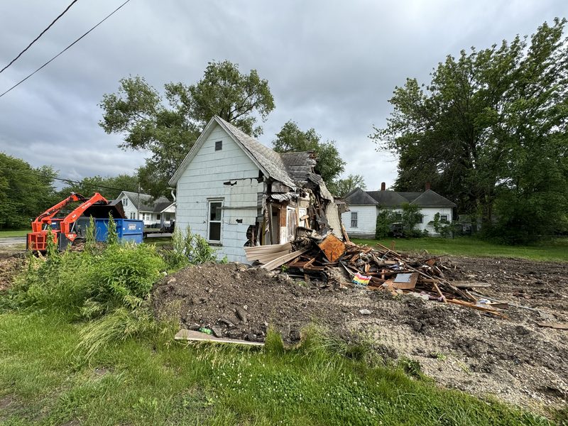 Demolition site in Mid-Missouri with the structure down and dirt staged next to the open foundation before backfill and lot grading