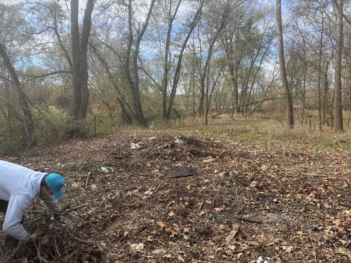 Atlas worker clearing brush along an overgrown fence line at the edge of a wooded field in Mid-Missouri