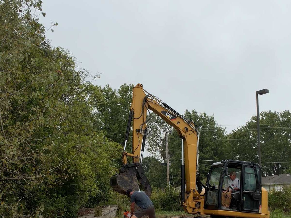 Excavator and crew on a graded gravel base ahead of a concrete pour in Columbia, MO