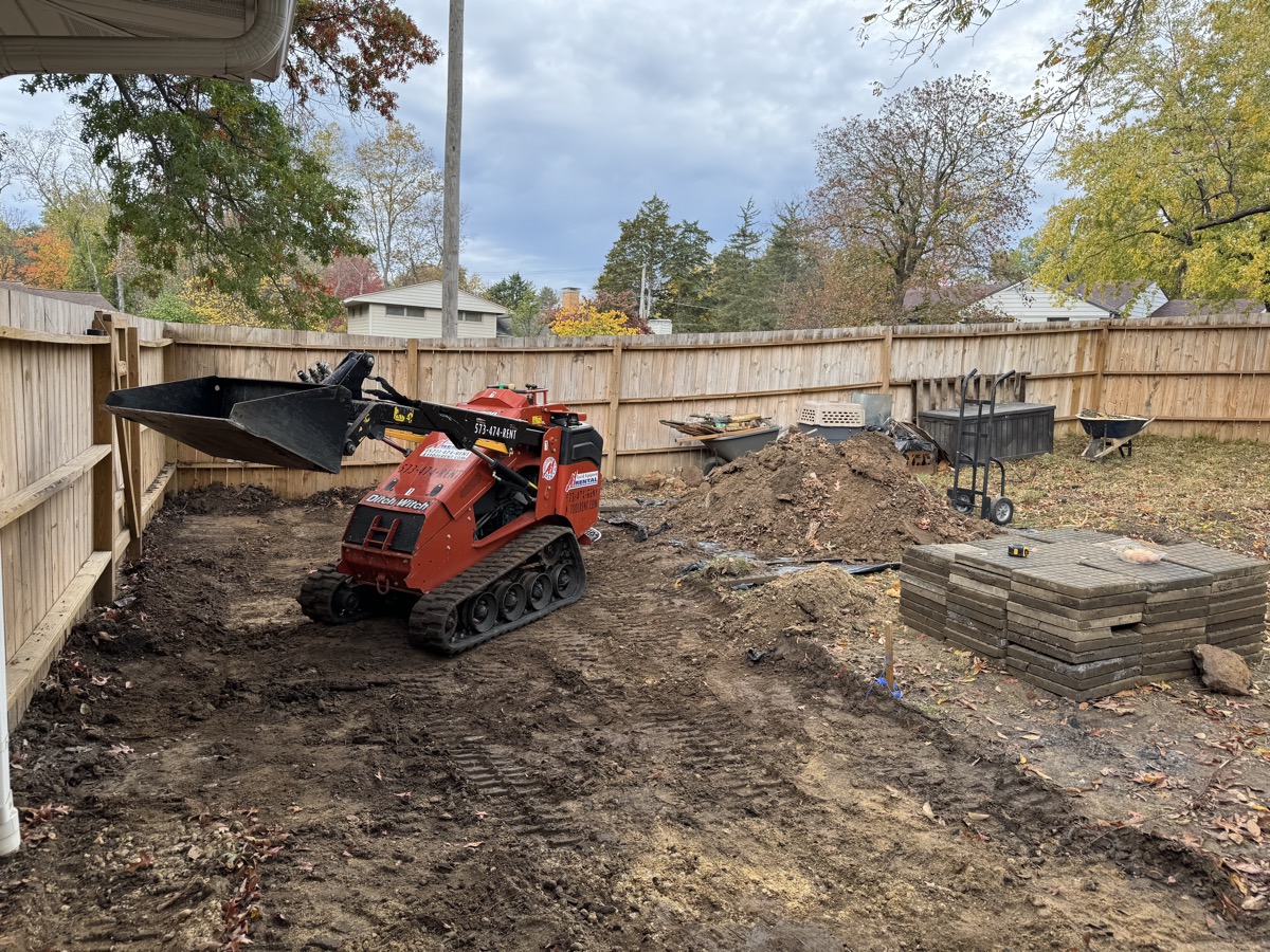 Skid steer excavating dirt near house foundation in Columbia, MO