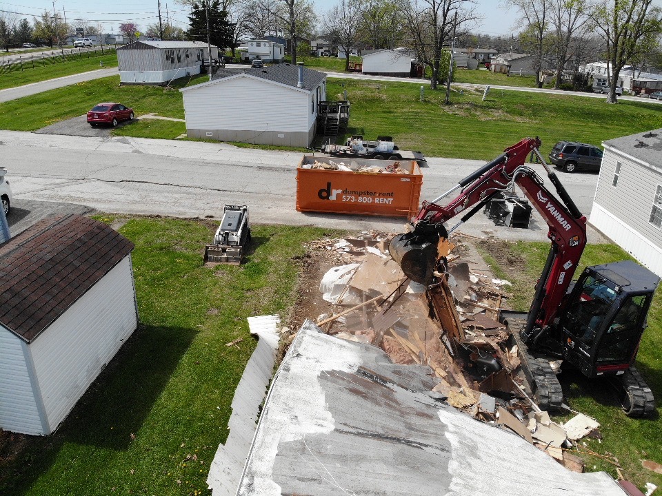 Atlas Excavation demolishing mobile home with excavator and dumpster in Columbia, Missouri