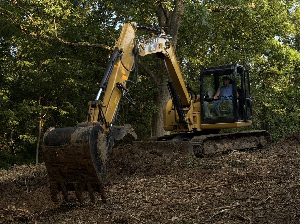 Excavator rough-grading a cleared lot after a demolition in Mid-Missouri