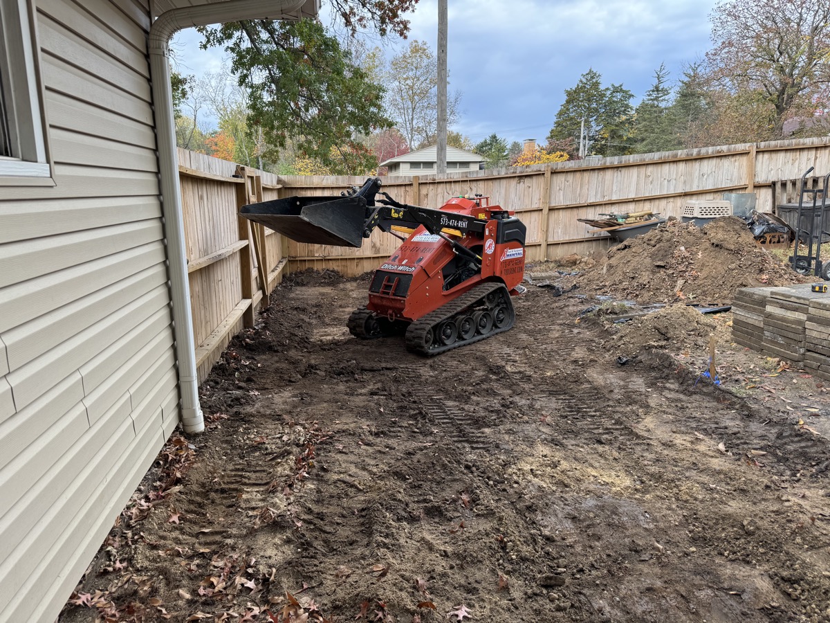 Skid steer digging and moving dirt for utility trenching project